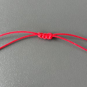May include: A close-up of a red cord tied in a knot.