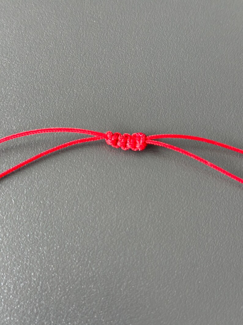 May include: A close-up of a red cord tied in a knot.