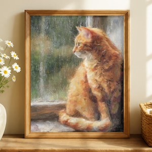 May include: A framed painting of a ginger cat sitting by a window. The cat is facing left, with its orange fur detailed. The painting has a gold frame and is set against a blurred, green background. The artwork is displayed on a wooden table.