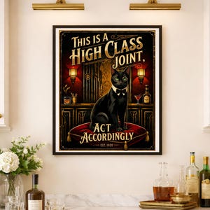 K&ouml;nnte beinhalten: Gerahmter Kunstdruck mit einer schwarzen Katze mit Monokel und Fliege auf einem roten Kissen. Der Druck lautet "THIS IS A HIGH CLASS JOINT, ACT ACCORDINGLY" in goldener Schrift, vor einem Vintage-Bar-Hintergrund.