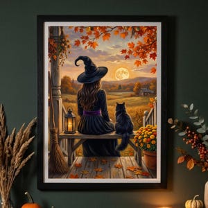 May include: A framed wall art print depicting a person in a black witch hat and dress sitting on a wooden porch with a black cat. The scene features a lantern, a broom, autumn leaves, a golden sunset, and a distant house in a field.