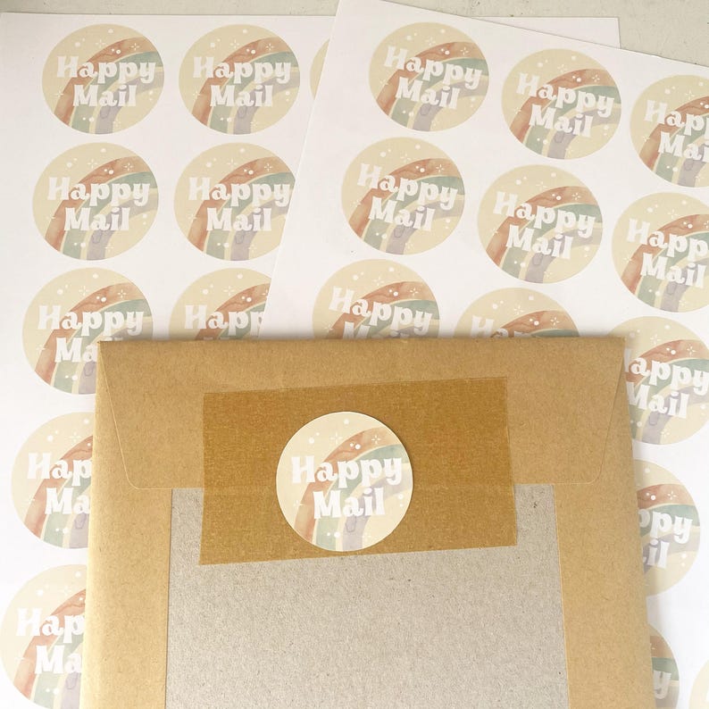May include: Round stickers with a rainbow design and the words "Happy Mail" in a soft, off-white font. The stickers are scattered around a brown paper envelope sealed with a matching sticker.