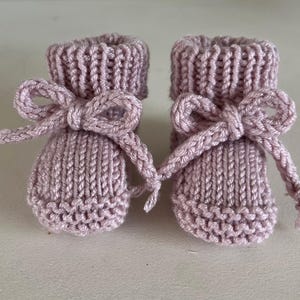 Puede incluir: Un par de patucos de beb&eacute; de punto en color lavanda suave. Cada patuco presenta un pu&ntilde;o acanalado y est&aacute; adornado con un lazo a juego. Los patucos est&aacute;n dise&ntilde;ados con un patr&oacute;n de punto texturizado.