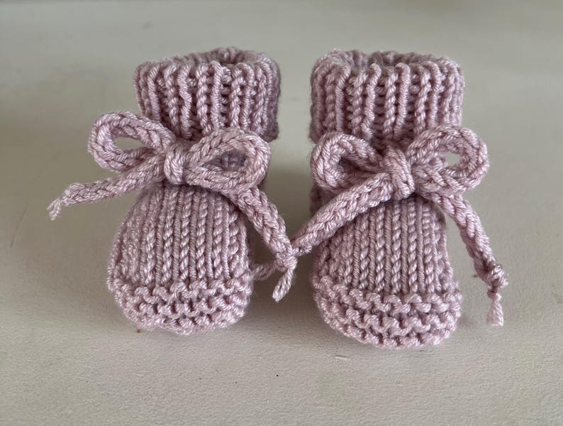 Puede incluir: Un par de patucos de beb&eacute; de punto en color lavanda suave. Cada patuco presenta un pu&ntilde;o acanalado y est&aacute; adornado con un lazo a juego. Los patucos est&aacute;n dise&ntilde;ados con un patr&oacute;n de punto texturizado.
