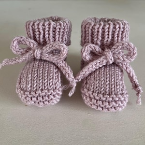 Puede incluir: Un par de patucos de beb&eacute; tejidos en color lavanda suave. Cada patuco tiene un lazo decorativo en la parte delantera. Los patucos est&aacute;n hechos de hilo texturizado, un regalo encantador para un reci&eacute;n nacido.