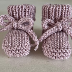 Puede incluir: Un par de patucos de beb&eacute; tejidos en color lavanda suave. Cada patuco presenta un lazo decorativo en el tobillo. Los patucos est&aacute;n hechos de un hilo texturizado, perfecto para un reci&eacute;n nacido.