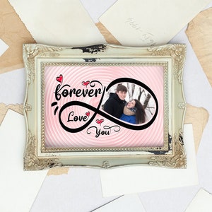 May include: A framed photo with a couple in a winter scene. The photo is surrounded by a pink and white swirl pattern with the text "forever love you" in black lettering with red hearts.