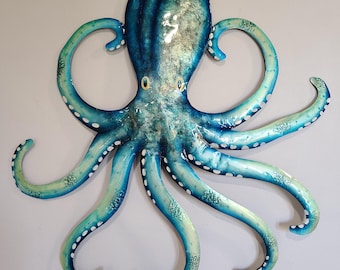 Könnte beinhalten: Eine blaue und grüne Metall-Oktopus-Wandskulptur mit weißen Punkten. Der Oktopus hat acht Tentakel und große, runde Augen.
