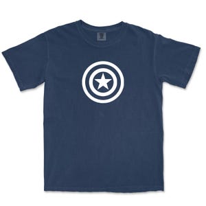 Puede incluir: Camiseta azul marino con un dise&ntilde;o blanco de una estrella dentro de un c&iacute;rculo. El dise&ntilde;o est&aacute; centrado en la parte delantera de la camiseta. La camiseta tiene mangas cortas y cuello redondo.