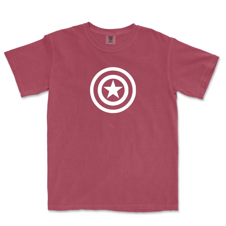 Puede incluir: Camiseta de color granate con un dise&ntilde;o gr&aacute;fico blanco de una estrella dentro de un escudo circular. La camiseta de manga corta est&aacute; hecha de un material suave y es adecuada para uso casual. El dise&ntilde;o est&aacute; centrado en la parte delantera.