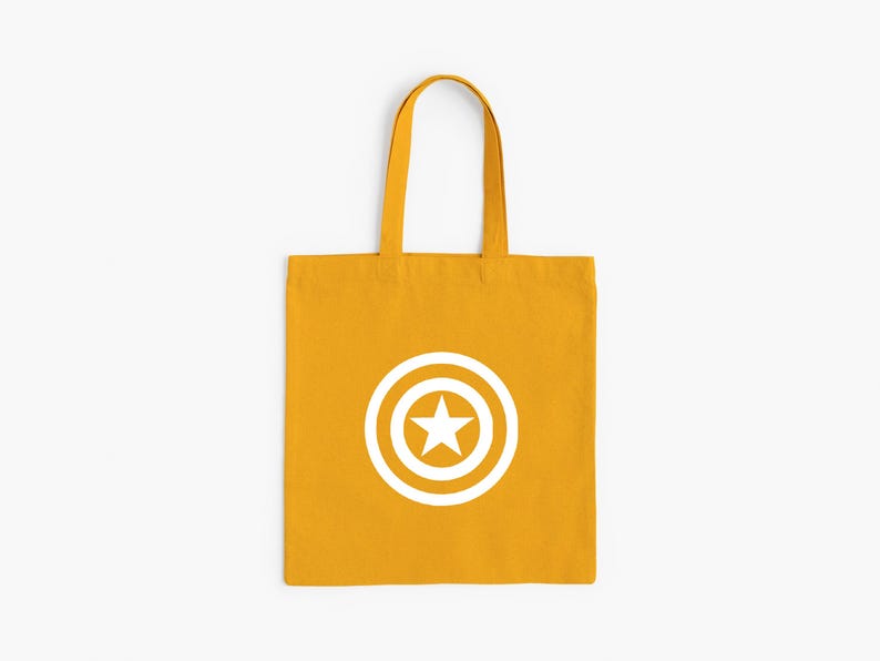 K&ouml;nnte beinhalten: Senfgelbe Tragetasche mit wei&szlig;em Captain America Schild-Design. Die Tasche hat eine rechteckige Form mit passenden Griffen. Die Grafik zeigt einen wei&szlig;en Stern in einem wei&szlig;en Kreis mit wei&szlig;em Rand.