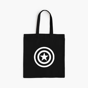 K&ouml;nnte beinhalten: Schwarze Tragetasche mit einem wei&szlig;en Stern-in-Kreis-Grafik. Die Tasche hat eine rechteckige Form mit einem Griff. Das Design befindet sich mittig auf der Vorderseite der Tasche.