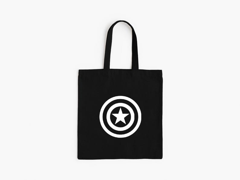 K&ouml;nnte beinhalten: Schwarze Tragetasche mit einem wei&szlig;en Stern-in-Kreis-Grafik. Die Tasche hat eine rechteckige Form mit einem Griff. Das Design befindet sich mittig auf der Vorderseite der Tasche.