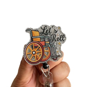 May include: Silver glitter badge holder with a wheelchair and the text "Let's Roll".