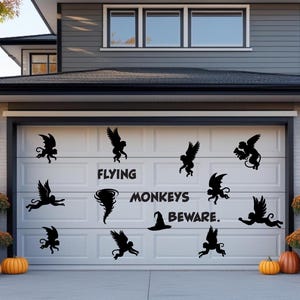 May include: A white garage door decorated with black silhouette decals of winged monkeys, a tornado, and a witch's hat. The text "FLYING MONKEYS BEWARE" is also displayed. Pumpkins and fall foliage decorate the front.
