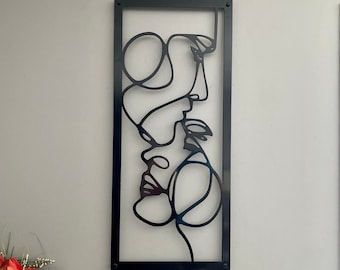 Puede incluir: Arte de pared de metal negro con un dibujo de línea de dos caras, una dentro de la otra. Las caras están delineadas en negro y el fondo es blanco.