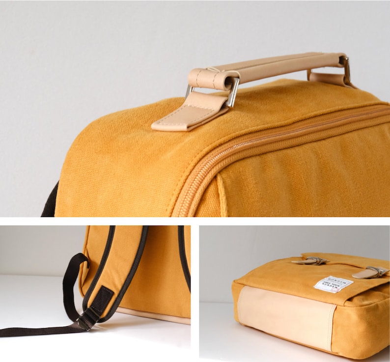 May include: A yellow canvas backpack with a brown leather handle and brown straps. The backpack has a zipper closure and a small pocket on the front.