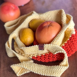 May include: A yellow and orange crocheted tote bag with a brown leather tag that says "Chickadee Crochet". The bag is filled with fruit, including a grapefruit, lemons, and an orange.