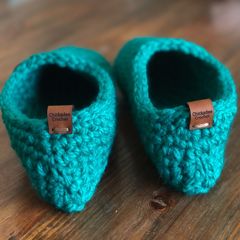 May include: A pair of teal blue crocheted slippers with brown leather tags that say "Chickadee Crochet".