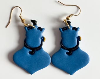 May include: A pair of blue earrings with a genie bottle design. The earrings have a gold-colored hook and a black accent around the neck of the bottle. The genie bottle shape is a vibrant blue color.