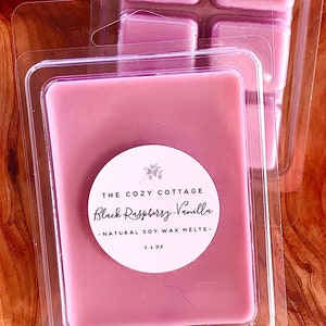May include: A package of four pink soy wax melts in a clear plastic container. The label reads "The Cozy Cottage Black Raspberry Vanilla - Natural Soy Wax Melts - 2.1 oz."