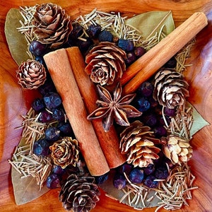May include: A wooden bowl filled with a variety of dried spices and herbs, including cinnamon sticks, star anise, pine cones, and juniper berries.