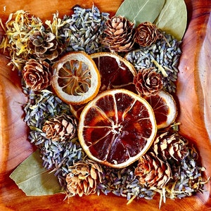 May include: A wooden bowl filled with dried lavender, lemon slices, pine cones, and bay leaves. The bowl is a natural wood color and the items inside are a mix of brown, green, and yellow.