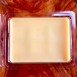 May include: A clear plastic container with a lid, containing a solid, pale yellow wax block.