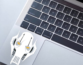 Può includere: Un adesivo bianco e grigio di Star Wars con il Generale Grievous con occhi gialli. L'adesivo è su una tastiera di un laptop.