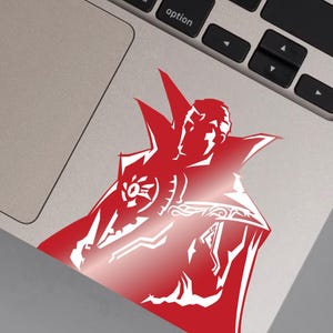 May include: Red silhouette of a superhero wearing a cape and a symbol on their chest. The silhouette is on a silver laptop.