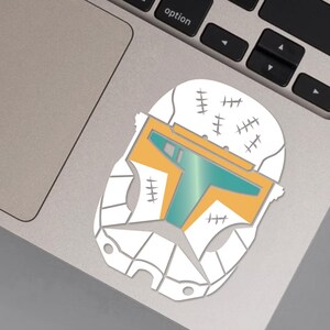 May include: White helmet sticker with a teal and orange design. The helmet has several stitches on the top and sides.