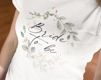 Bride to be T-Shirt im modernen, zarten gold-grünen Blätterdesign zum JGA, klassisches weißes Baumwoll-T-Shirt im unisex Schnitt