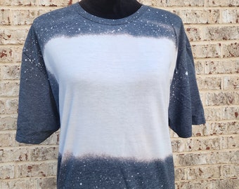 May include: A dark blue t-shirt with a white bleached design. The shirt has a speckled pattern throughout.
