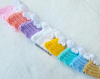 May include: A set of nine crocheted doll dresses in various colors, including pink, orange, purple, white, yellow, blue, and brown. The dresses are arranged in a row, with the pink dress at the top and the brown dress at the bottom. The dresses are all made with a delicate crochet stitch and have a ruffled trim. The dresses are all about 3 inches long and are perfect for doll clothes or other craft projects. @favecrochet
