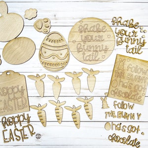May include: A set of unfinished wooden Easter craft supplies, including bunny shapes, carrots, eggs, and signs with the text "Shake your bunny tail" and "Follow the bunny, he's got chocolate".