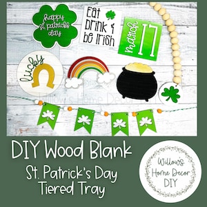 May include: DIY wood blank tiered tray with a St. Patrick's Day theme. The tray includes a green shamrock, a rainbow, a pot of gold, a horseshoe, and a banner with shamrocks. The text "Eat Drink & Be Irish" and "March 17" are also included.