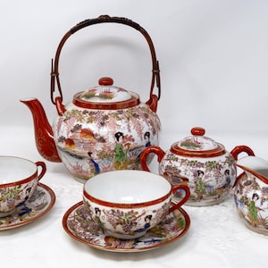 May include: A Japanese tea set comprising a teapot, creamer, sugar bowl, and two teacups. The set is decorated with a floral pattern and features a traditional Japanese design.