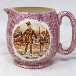 Könnte beinhalten: Lilafarbener Keramik Krug mit Henkel, mit einer Vintage-Illustration von zwei Männern, die eine Straße entlang gehen. Die Illustration enthält den Text "Micawber Introduces David to London".