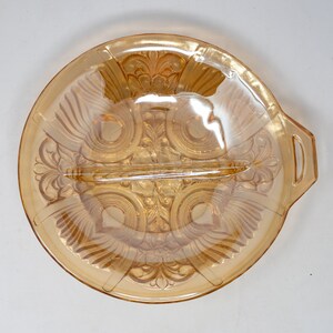 May include: A divided amber glass serving dish with a decorative floral pattern. The dish has two handles and a central divider.