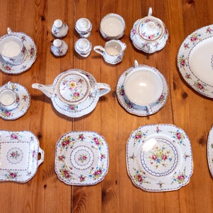 May include: A set of white porcelain teacups, saucers, and plates with a floral pattern. The set includes a teapot, sugar bowl, creamer, and a serving platter.