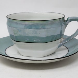 May include: A white teacup and saucer set with a blue and white striped design. The cup has a rounded shape and a handle. The saucer has a matching design.