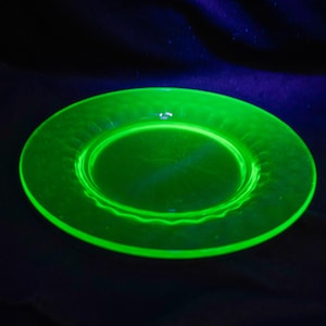 Könnte beinhalten: Ein leuchtend grüner Glasteller mit einem gewellten Rand. Der Teller ist aus Uran-Glas und leuchtet unter Schwarzlicht.