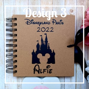 May include: A brown notebook with a black spiral binding. The cover features a black silhouette of the Disneyland Paris castle with Mickey Mouse ears in the center. The text "Disneyland Paris 2022" is printed above the castle and the name "Alfie" is printed below the castle.