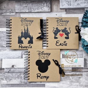 May include: Three brown spiral bound notebooks with black ribbon closures. Each notebook has a different Disney character design and the text "Disney 2025" on the front cover. The names "Aurelia", "Eadie", and "Remp" are printed on the front covers.