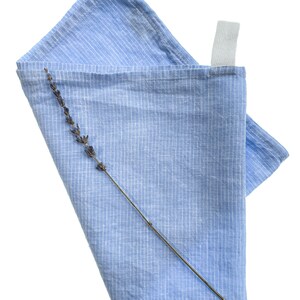 May include: A blue striped linen tea towel with a dried lavender sprig on top.