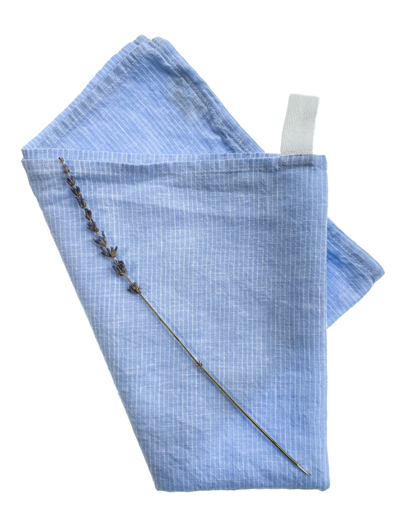 May include: A blue striped linen tea towel with a dried lavender sprig on top.
