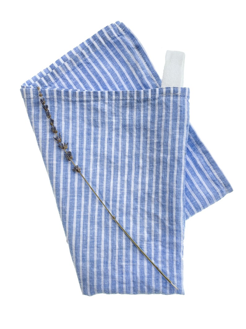 May include: A blue and white striped kitchen towel with a lavender sprig on top. The towel has a white loop sewn on the top corner.