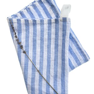 May include: A blue and white striped linen kitchen towel with a loop handle and a sprig of lavender.