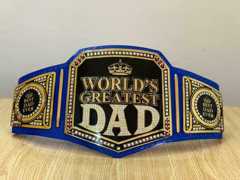 May include: A blue and gold championship belt with the words "World's Greatest Dad" and a crown on the front. The belt has two side plates that say "Best Dad Ever".
