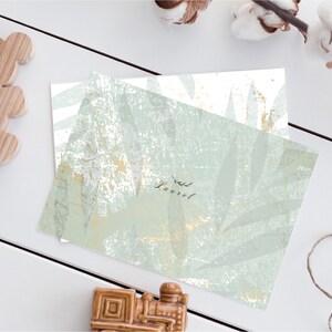 May include: A white card with a green and gold leaf pattern. The card has the word "Laurel" written on it in black script.